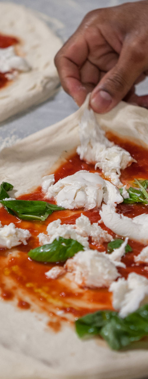 Preparing fresh pizza with mozzarella and basil