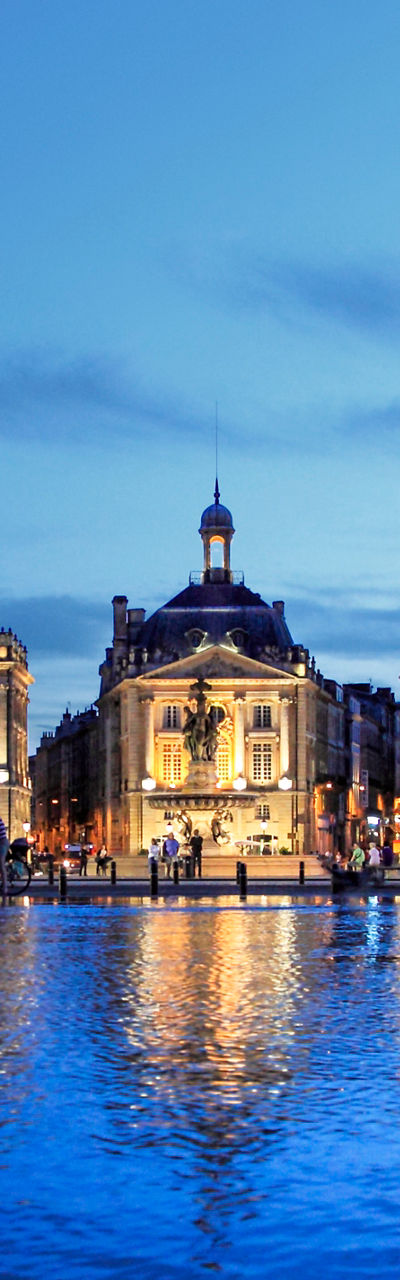 Illuminated Bordeaux cityscape with water reflection