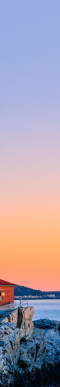 Scenic lighthouse at sunset by rocky coast