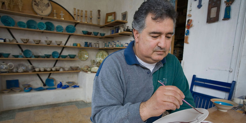 Artisan painting ceramic plate in workshop
