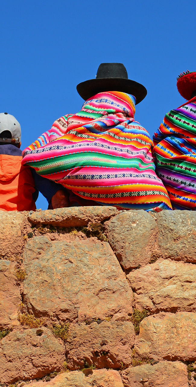 Group in colorful traditional attire on stone wall