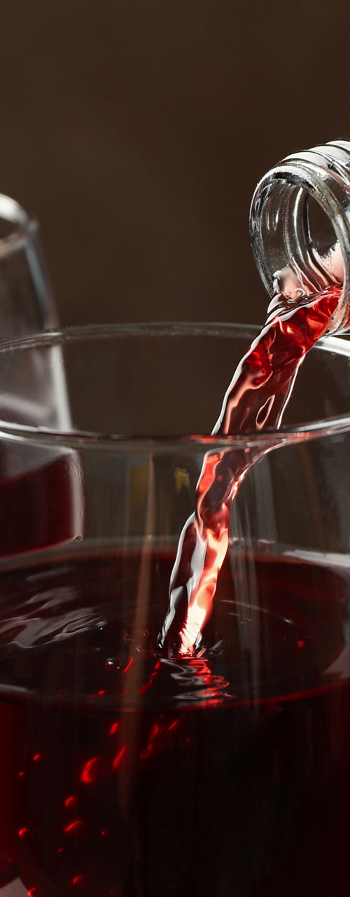 Red wine poured into glass with grapes nearby