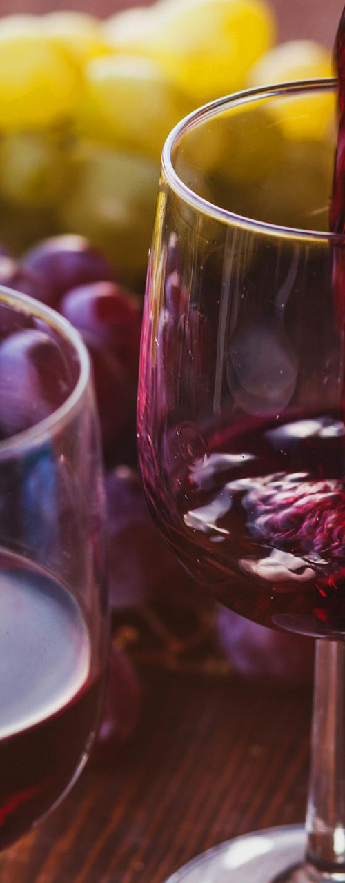 Pouring red wine with fresh grapes