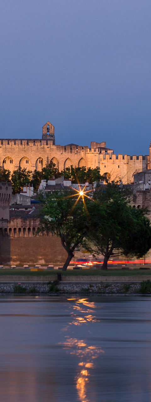 Historic castle by river at dusk
