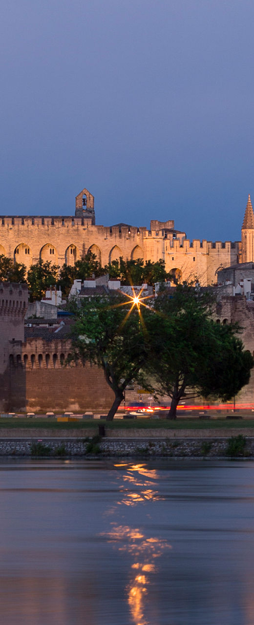 Historic castle by river at dusk