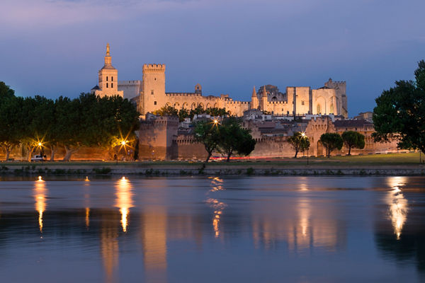 Historic castle by river at dusk