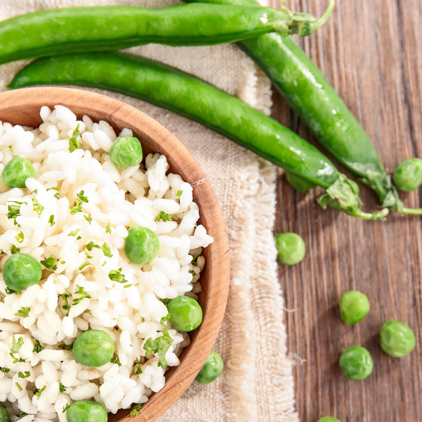 Fresh green pea risotto in wooden bowl