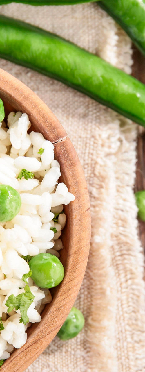 Fresh green pea risotto in wooden bowl
