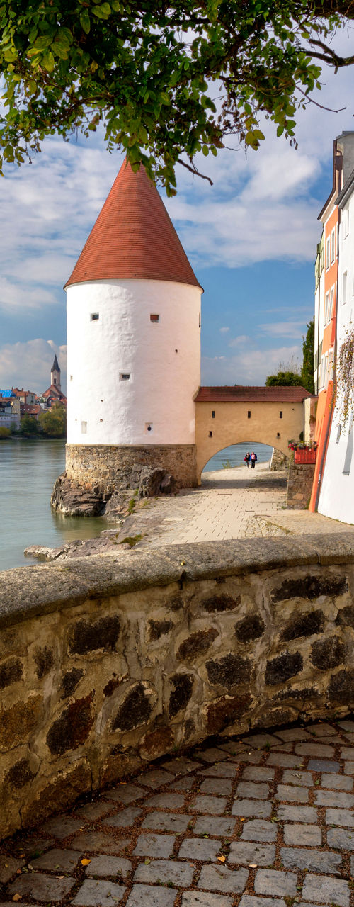 Historic riverside tower with cobblestone path