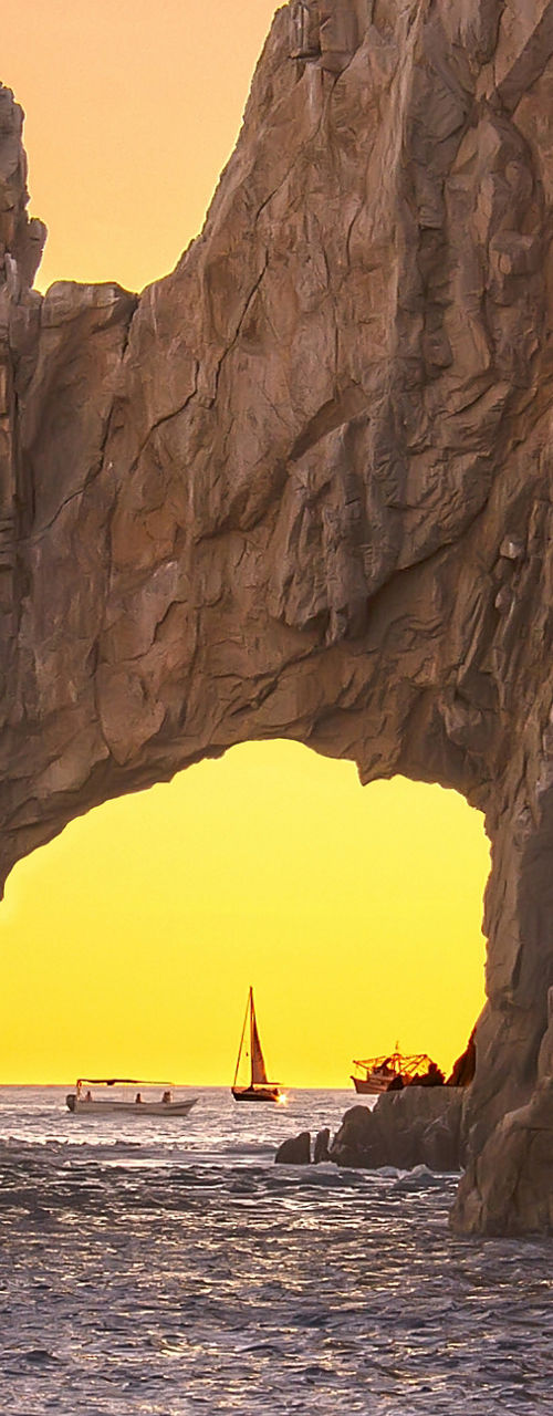 Sunset at natural rock arch over ocean