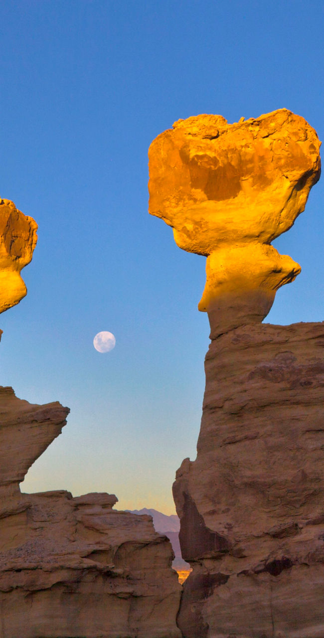 Sunlit rock formations with moonrise