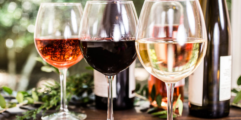 Assorted wine glasses with bottles in background