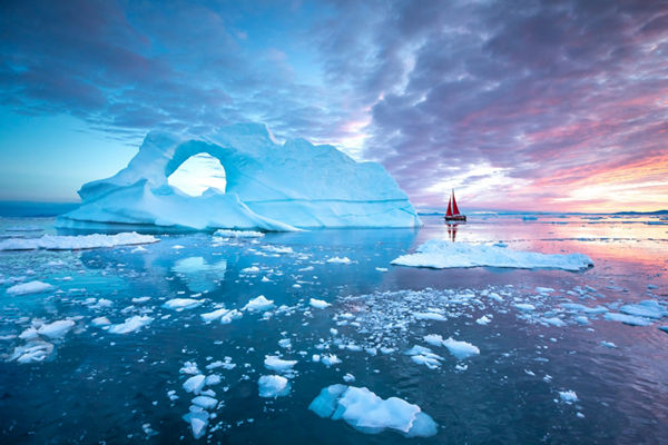 Sailboat near iceberg at colorful sunset