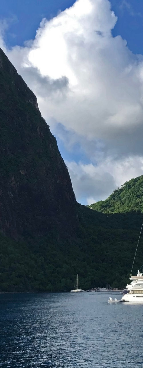 Sailboat on tropical bay beneath lush peak
