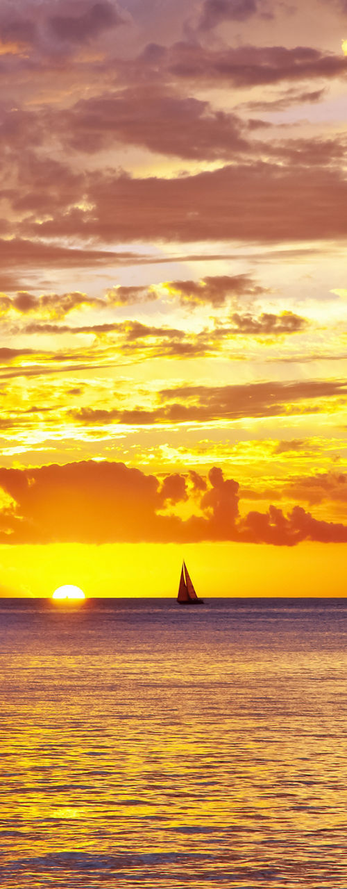 Sailboats at sunset over calm ocean