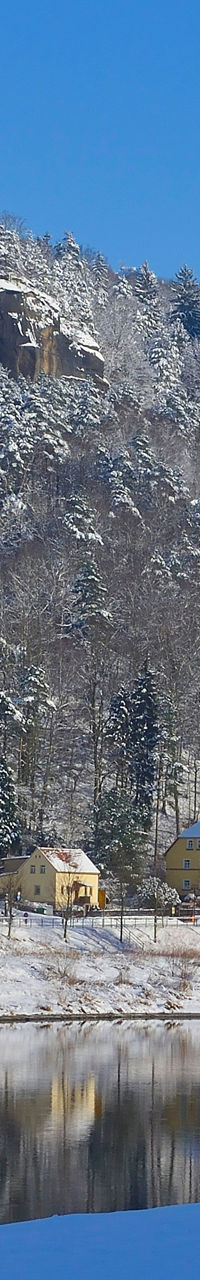 Snowy riverside village beneath rocky cliffs