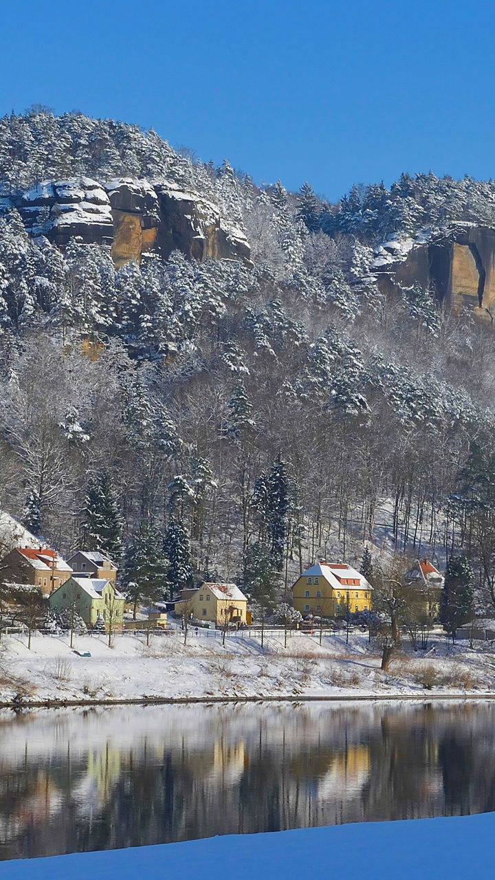 Snowy riverside village beneath rocky cliffs