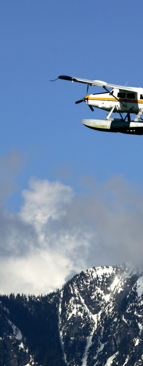 Seaplane flying over snowy mountain range