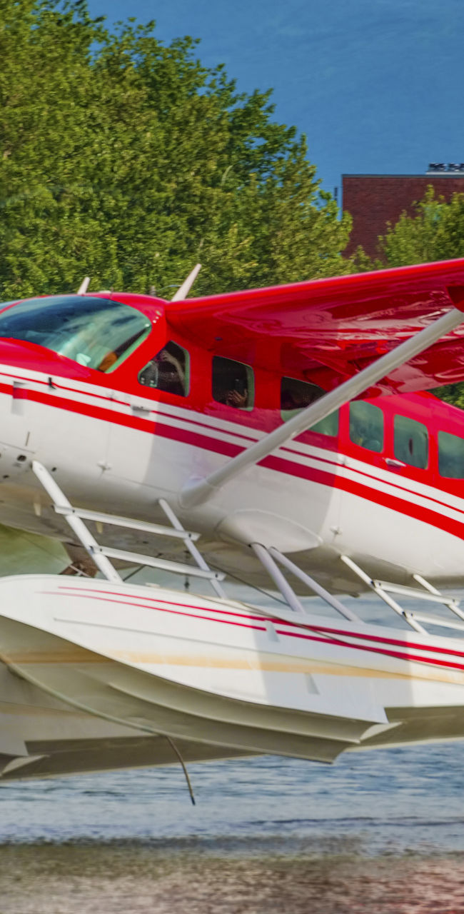 Red seaplane landing on calm water