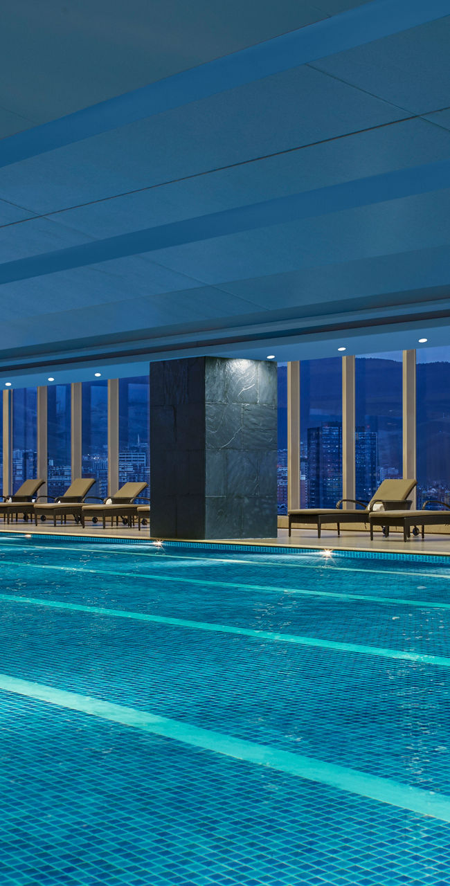 Modern indoor rooftop swimming pool at dusk