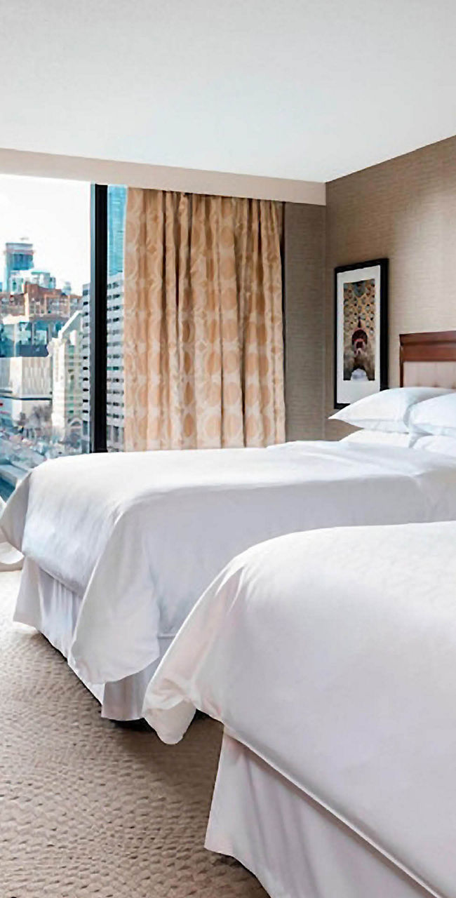 Modern hotel room with two double beds and city view
