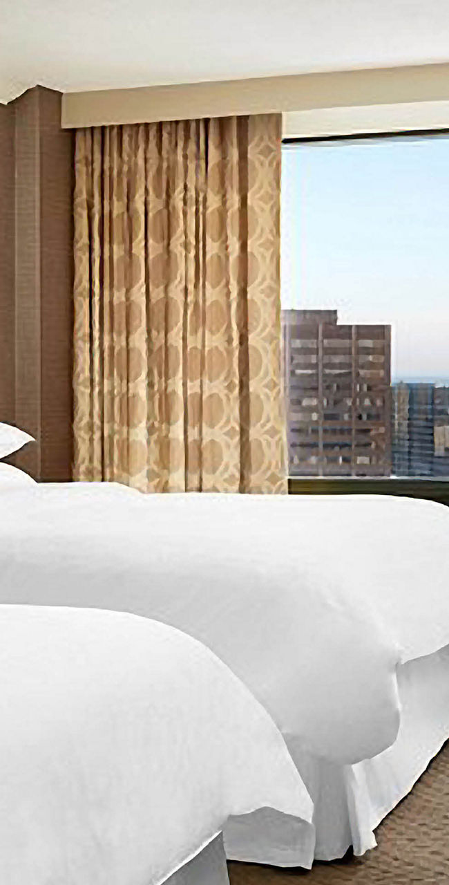 Modern hotel room with city skyline view and twin beds
