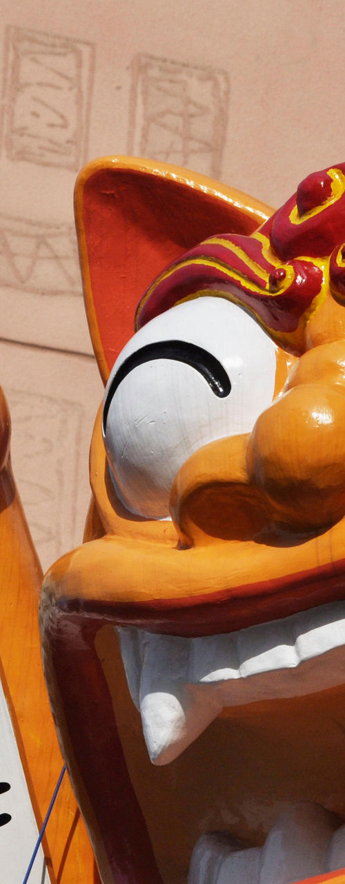 Large orange maneki-neko statue in sunlight