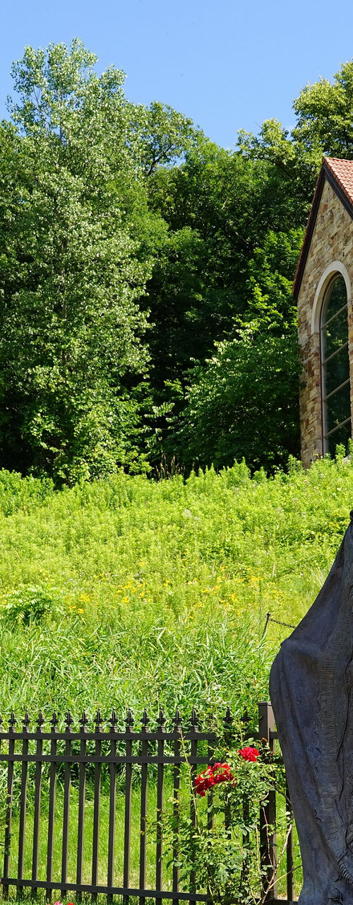 Stone chapel with garden statue in summer