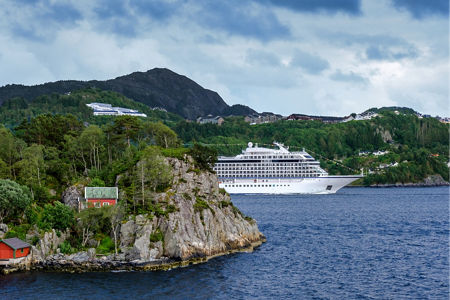 White cruise ship near rocky coastline
