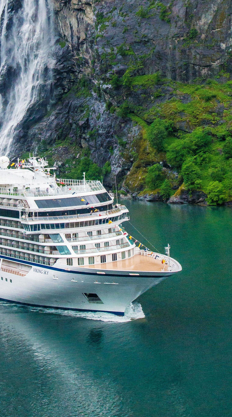 Cruise ship near scenic waterfall and cliffs