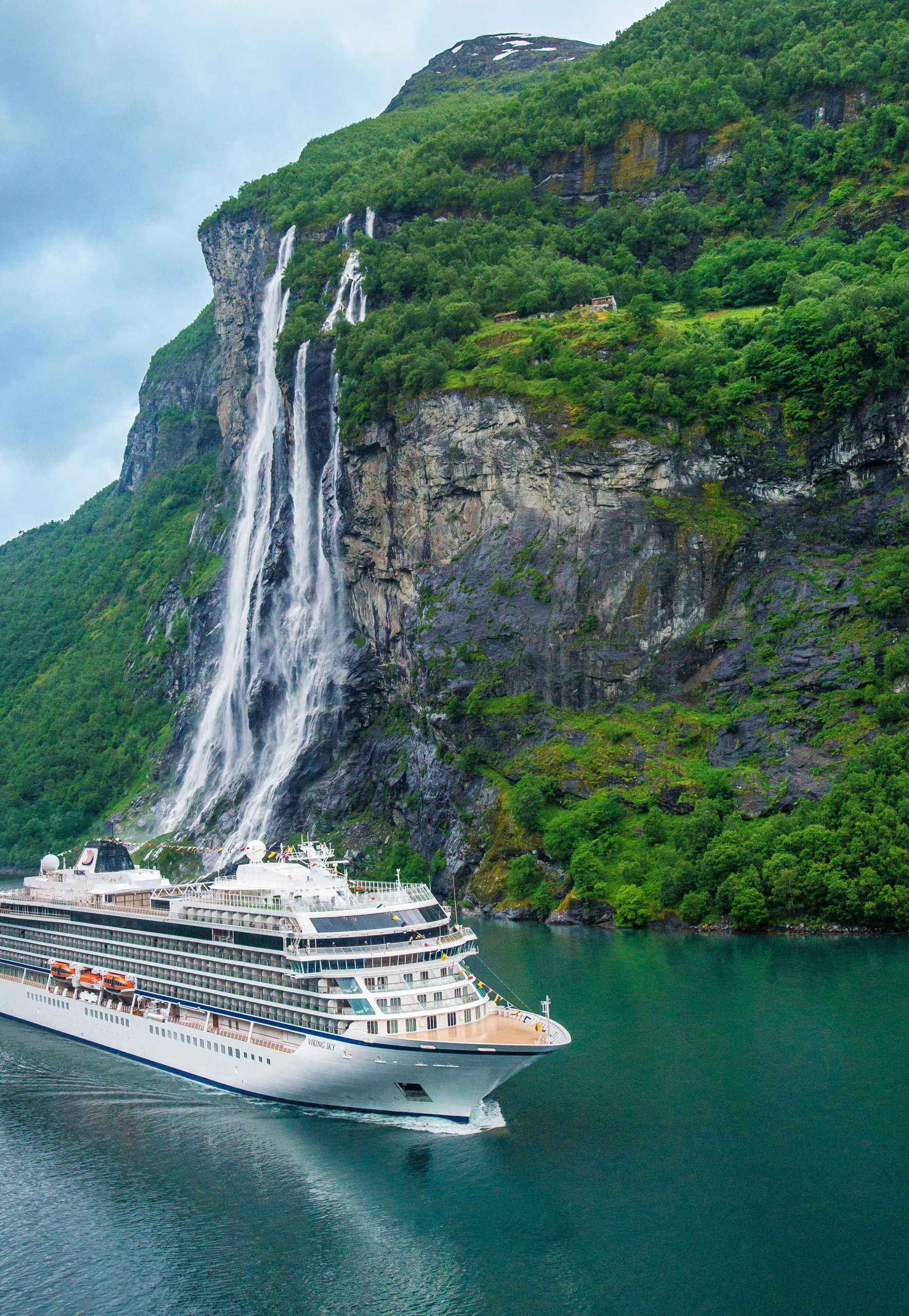 Cruise ship near scenic waterfall and cliffs