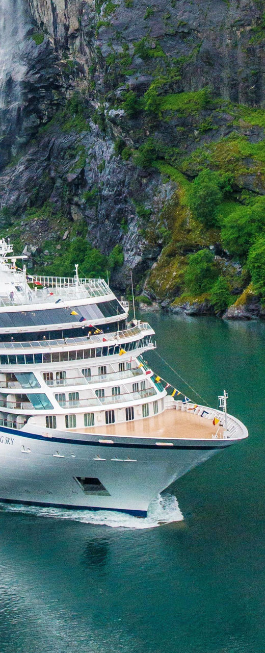Cruise ship near scenic waterfall and cliffs