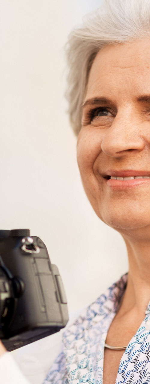Smiling mature woman holding digital camera
