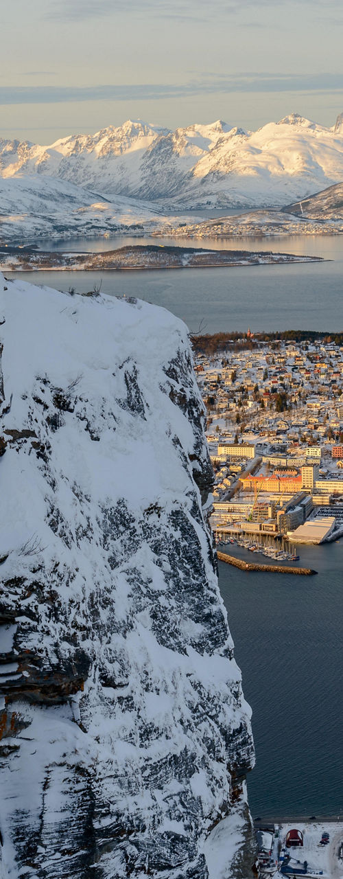 Snowy cliff overlooking Arctic town and fjord