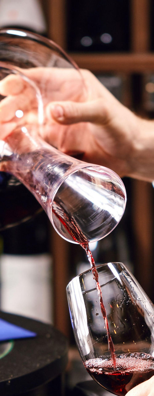 Sommelier pouring red wine in glass