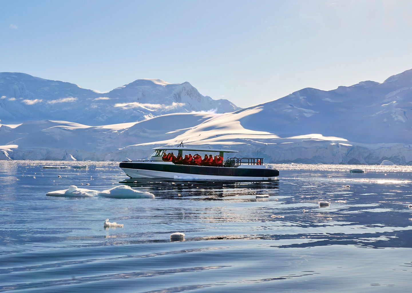 Tour boat in icy Arctic waters under sun