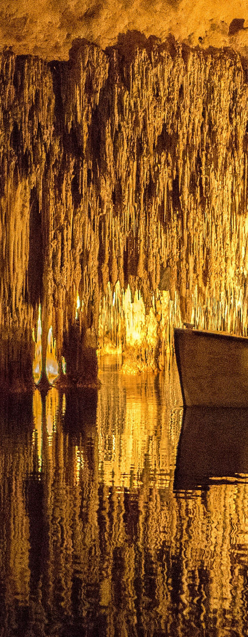 Illuminated boat in underground cave lake