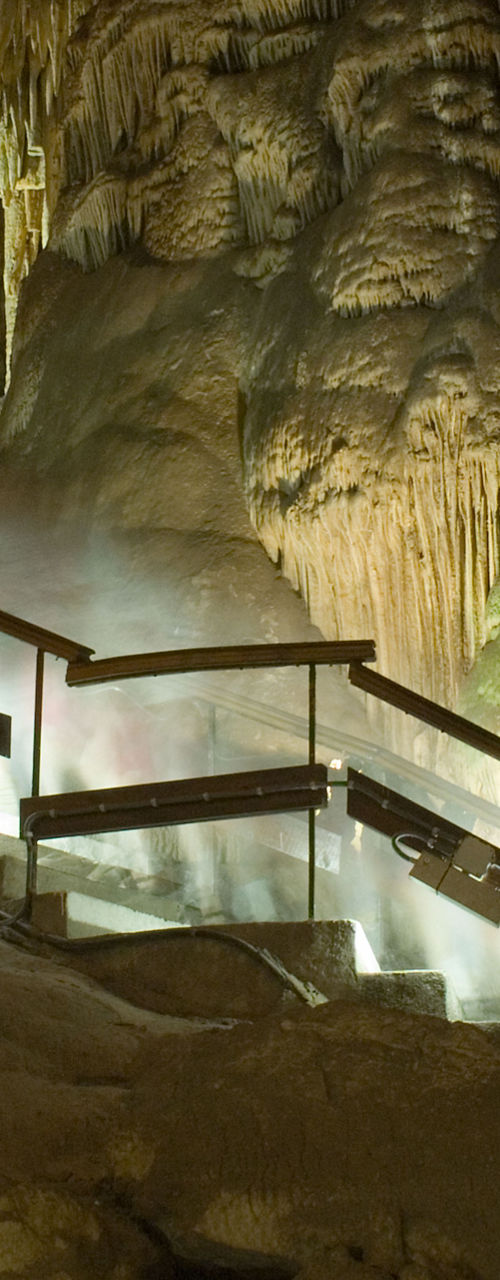 Illuminated cave staircase with stalactites