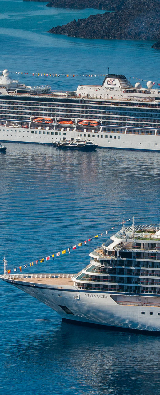 Two large cruise ships anchored near volcanic island