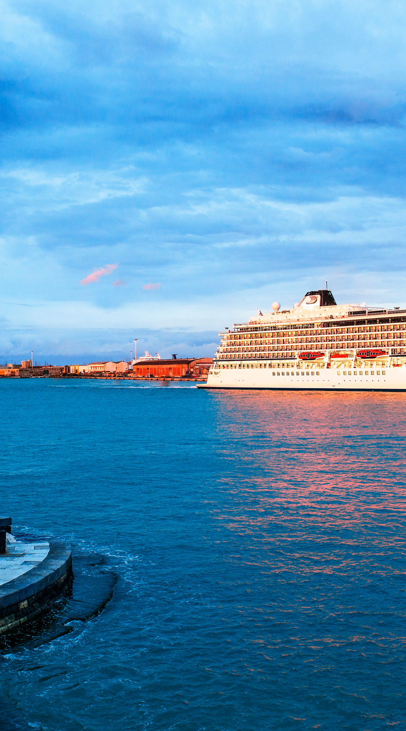 Cruise ship near coastal lighthouse at sunset