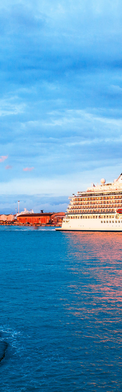 Cruise ship near coastal lighthouse at sunset