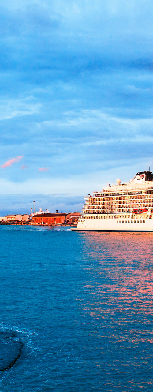Cruise ship near coastal lighthouse at sunset