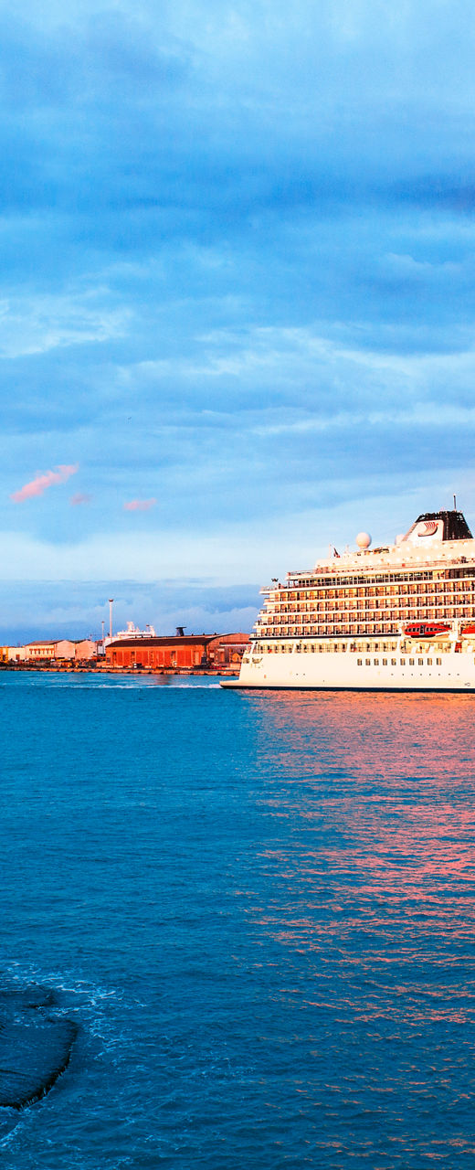 Cruise ship near coastal lighthouse at sunset