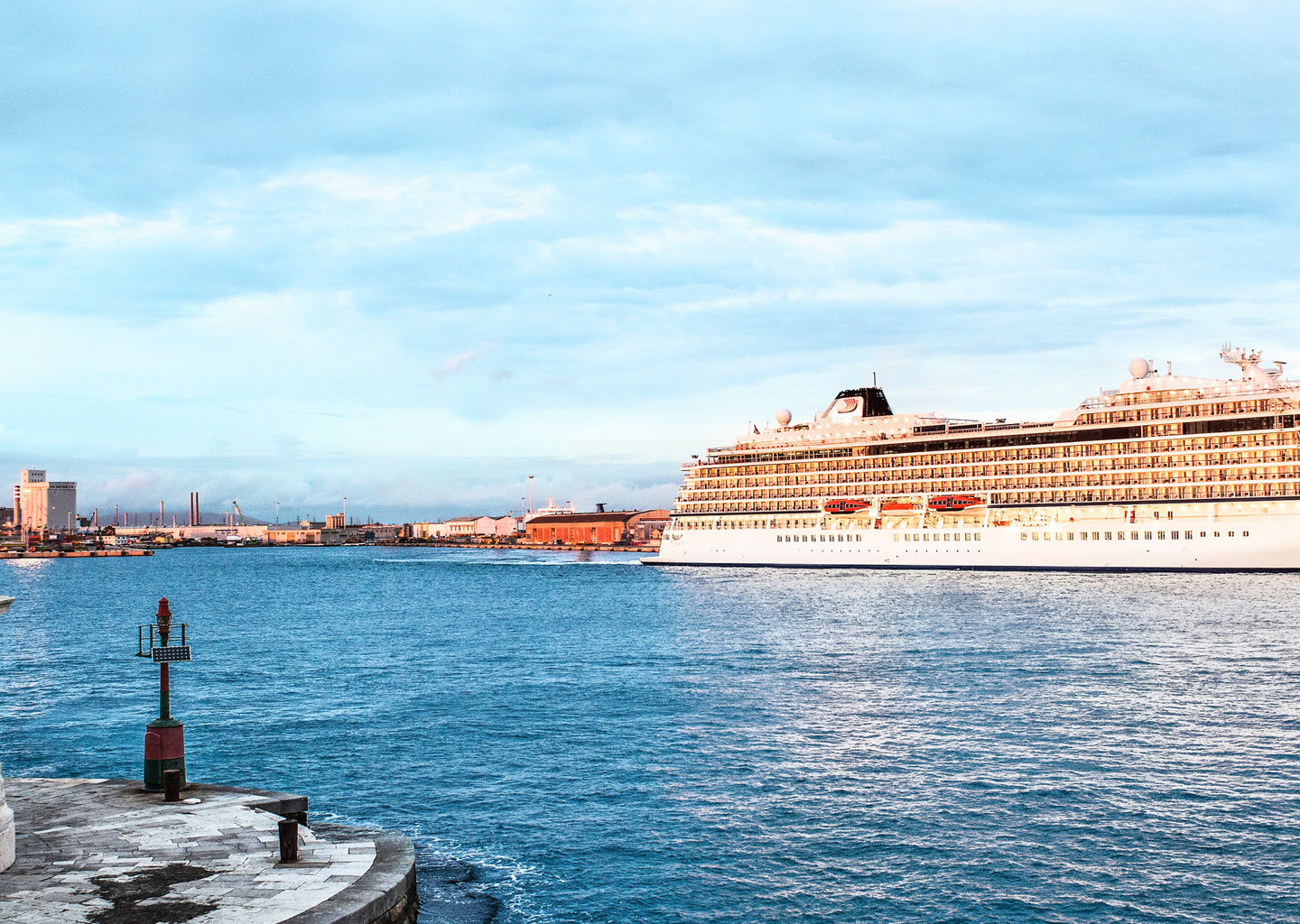Cruise ship near coastal lighthouse at sunset