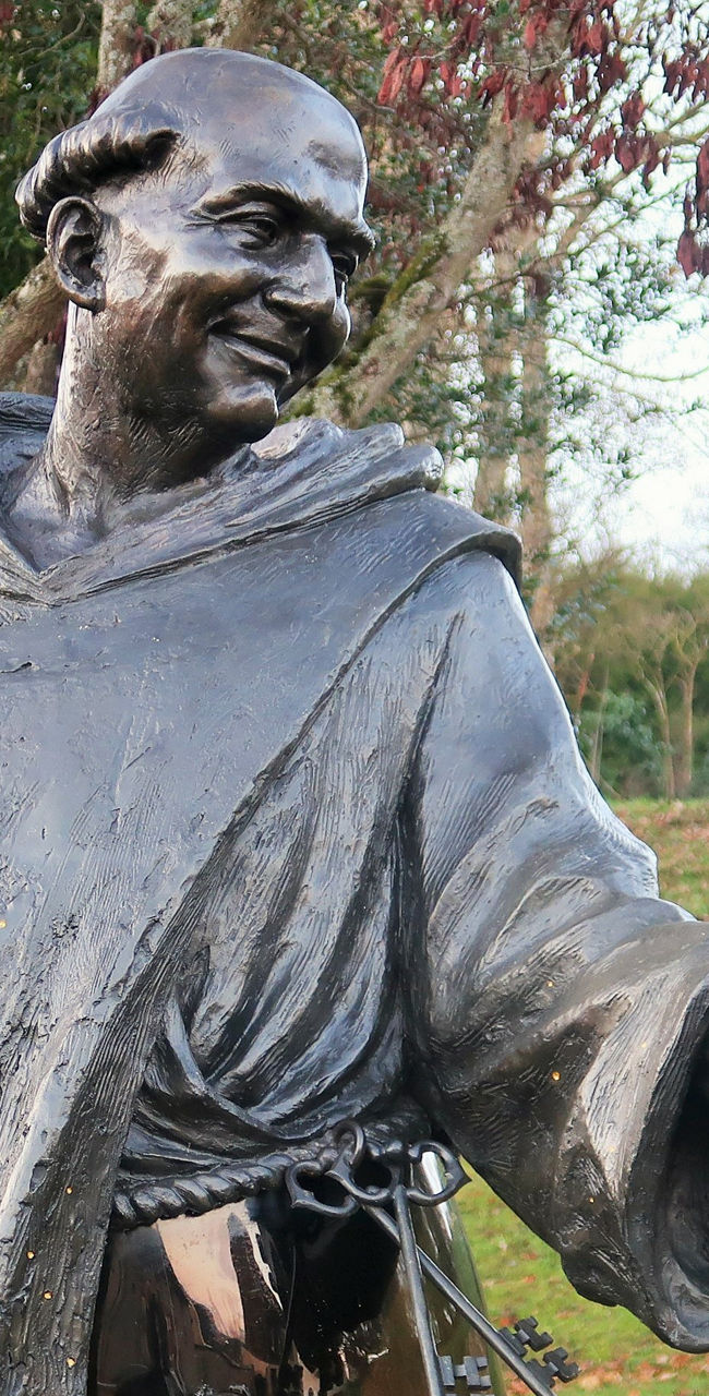 Bronze statue of monk holding grapes and glass