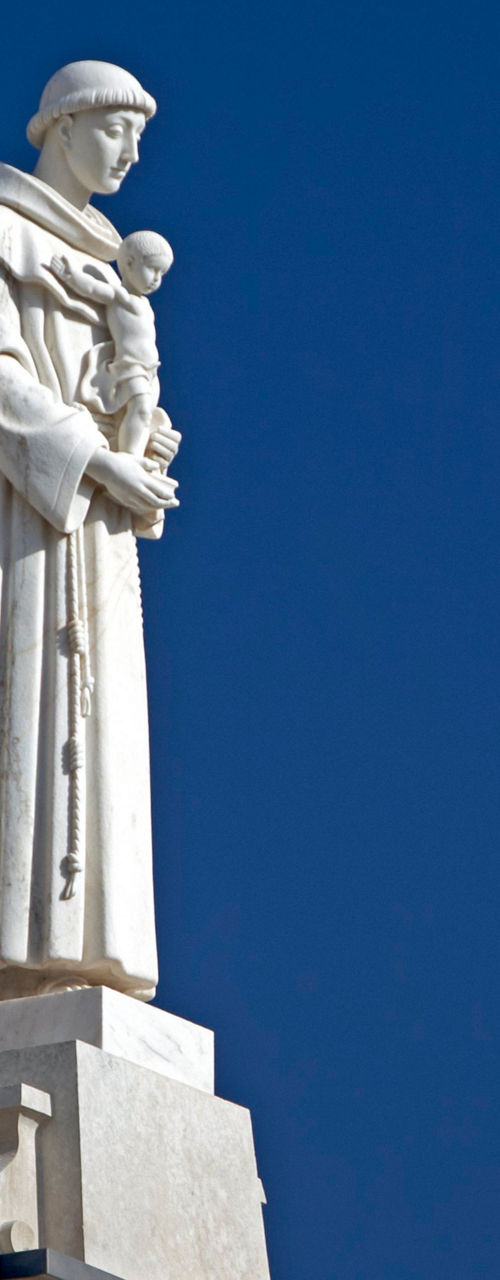 Statue of Saint holding child under blue sky
