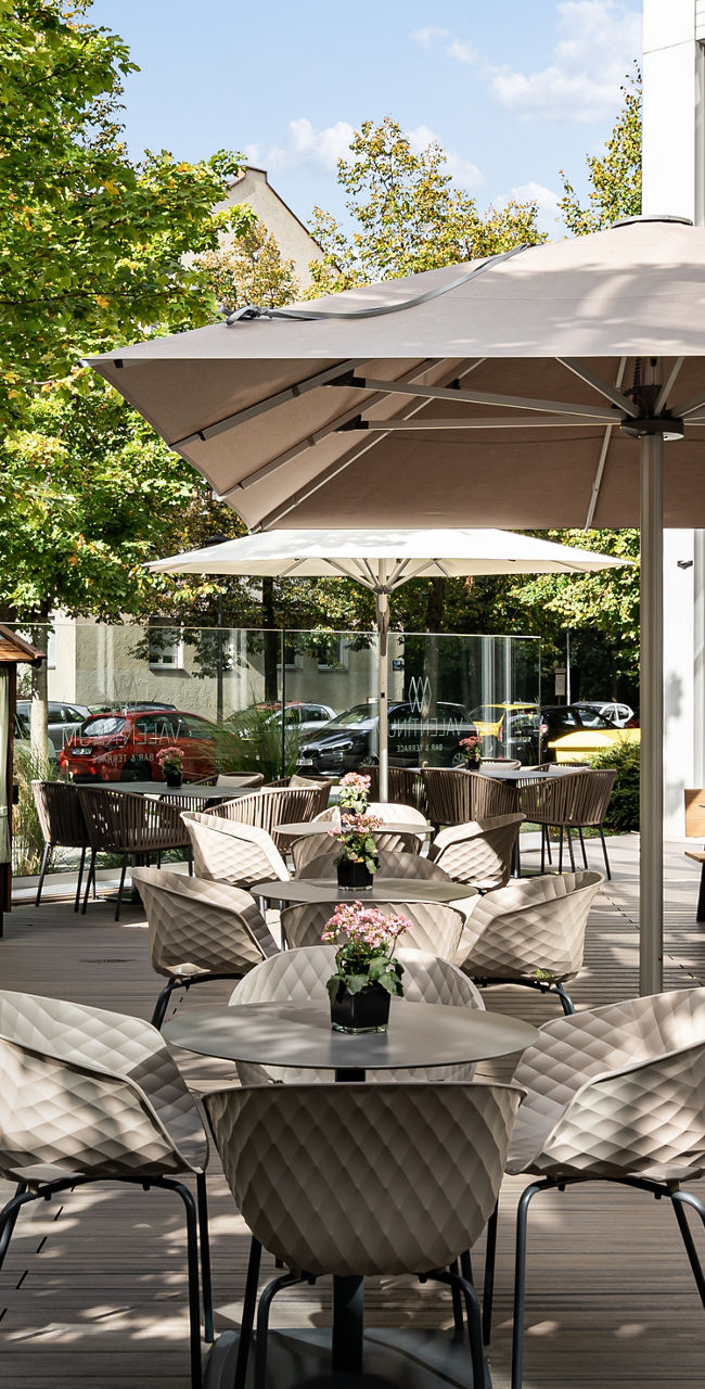 Outdoor cafe seating with umbrellas and greenery