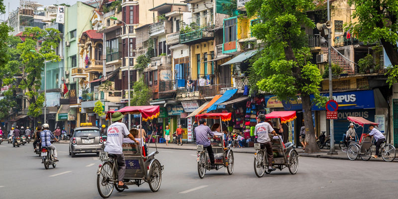 Cyclo riders in bustling Hanoi street