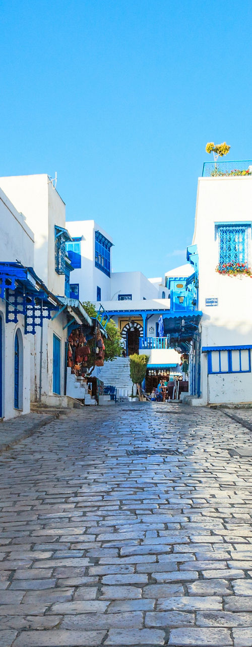Sunlit cobblestone street with blue doors