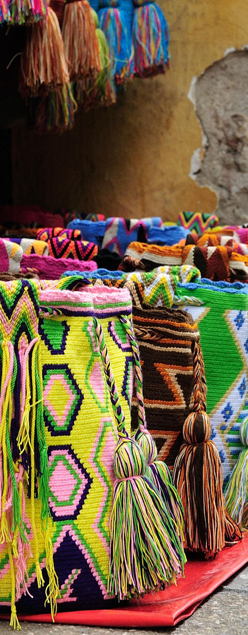 Colorful woven bags displayed on rustic street